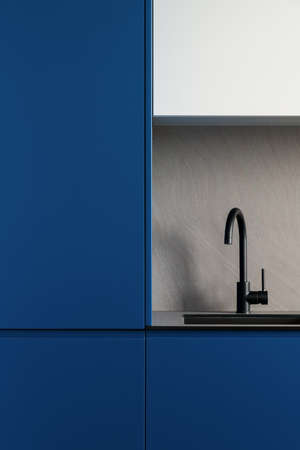 Close-up on modern designed kitchen with navy blue kitchen furniture, fridge and stylish black sink with black tapの写真素材