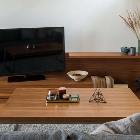 Close-up on wooden coffee table with decorations in living room with big tv on wooden sideboardの写真素材