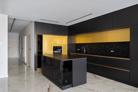 Spacious and luxury kitchen with marble floor, black and golden cupboards and stylish kitchen island with black countertopの写真素材