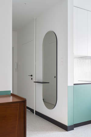 Modern oval mirror in apartment corridor with white doors and terrazzo floorの写真素材
