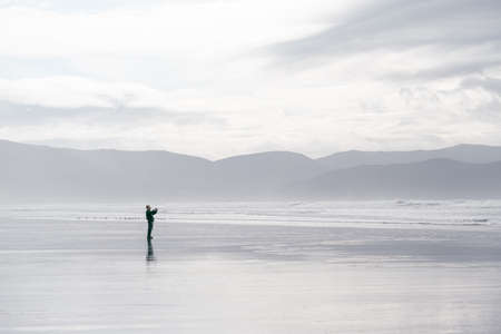 Man taking pictures on amazing Inch Beach in Dingle Peninsula, Irelandの写真素材