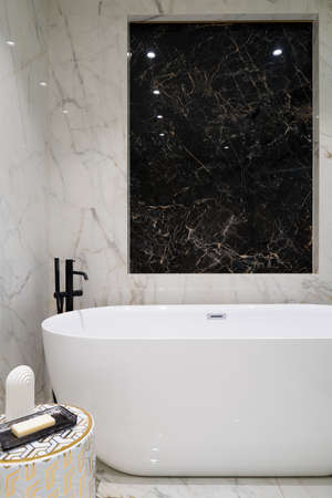 Fancy bathroom with black and white marble tiles on wall and floor and luxury freestanding bathtubの写真素材