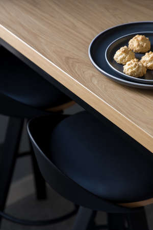 Close-up on black chairs under wooden table with cookies on decorative platesの写真素材