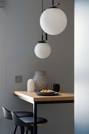 Stylish decorations on wooden table with two black chairs under modern pendant lampsの写真素材