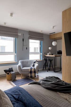 Modern and small studio apartment with bedroom open to kitchen and cozy armchairの写真素材