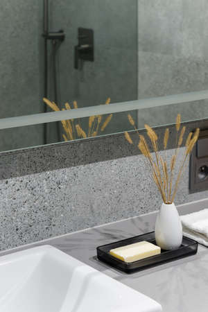Soap bar and decorations next to washbasin in modern bathroom with big mirror and terrazzo style tilesの写真素材