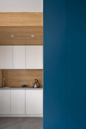 Stylish kitchen with wooden ceiling, granite floor and white furniture and with navy blue wallの写真素材