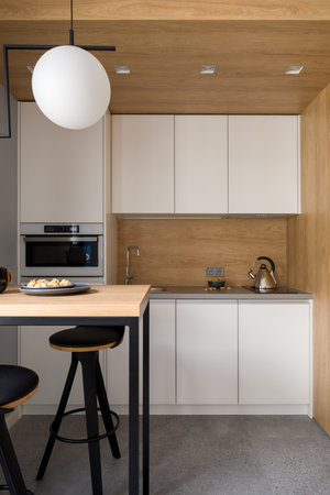 Stylish kitchen with wooden walls and ceiling, white cupboards and small table with two chairsの写真素材