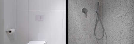 Panorama of modern and simple bathroom with terrazzo tiles and spacious shower cabin next to toiletの写真素材