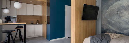 Panorama of stylish designed studio apartment with kitchen next to bedroom with tvの写真素材