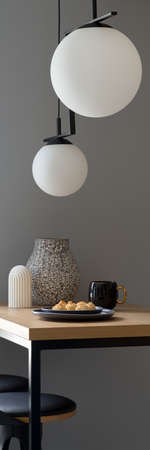 Vertical panorama of stylish decorations on wooden table under modern pendant lampsの写真素材