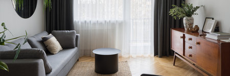 Panorama of eclectic living room with retro style, wooden sideboard and with simple and modern sofa and coffee table and big windowの写真素材