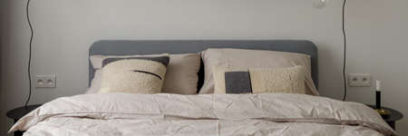 Panorama of comfortable bed with gray headboard and simple and elegant bedclothesの写真素材