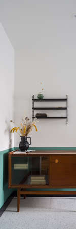 Vertical panorama of vintage, wooden sideboard with decorative vase and books in modern apartment with stylish terrazzo on the floorの写真素材