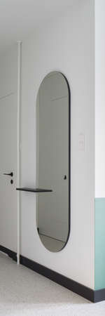 Vertical panorama of modern oval mirror in apartment corridor with white doors and terrazzo floorの写真素材