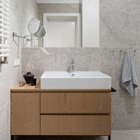 Modern bathroom with patterned wall and floor tiles, big washbasin in wooden cabinet and big mirrorの写真素材