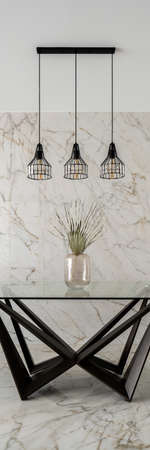 Vertical panorama of black lamps over modern dining table in stylish dining room with marble wall and floor tilesの写真素材