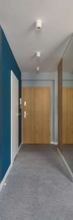 Vertical panorama of modern corridor with terrazzo floor tiles, navy blue wall with white doors and wall with mirrorの写真素材