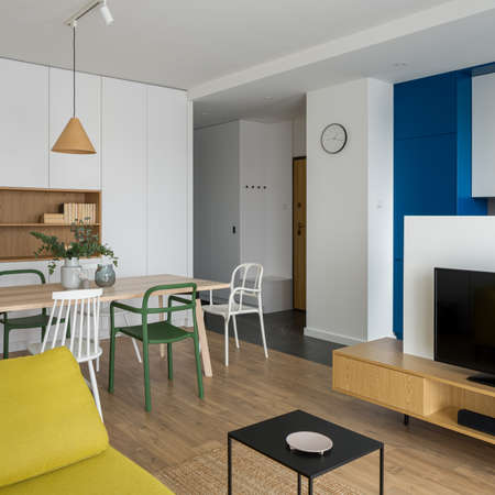 Simple and modern dining table with different white and green chairs in stylish open plan apartmentの写真素材