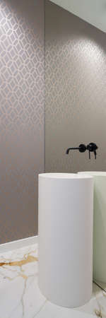 Vertical panorama of modern washbasin tub with black tap in mirror wall in stylish bathroom with wallpaper and marble floor tilesの写真素材