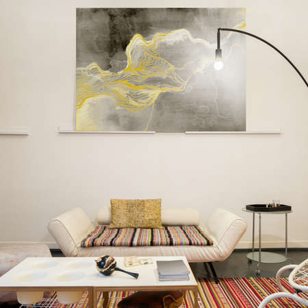 Uncommon design in living room with artistic decorations, creative furniture, modern lighting and big painting on the wallの写真素材
