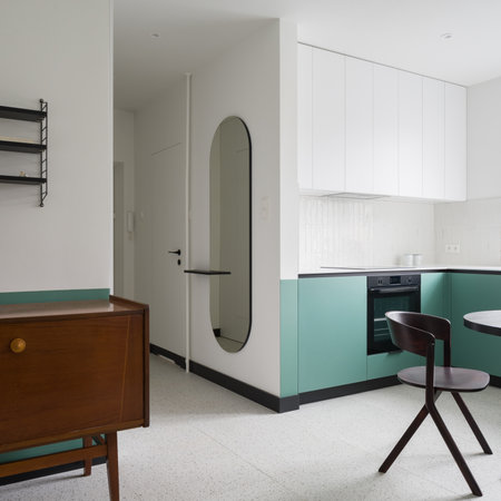 Stylish oval mirror in corridor next to modern green and white kitchen with terrazzo floorの写真素材