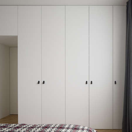 Spacious bedroom with many, big, white wardrobes with black handlesの写真素材