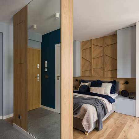 Stylish bedroom with cozy bed with decorative bedclothes behind wall with mirrorの写真素材