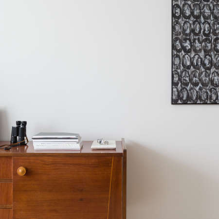 Close-up on decorations and books on wooden, vintage sideboard and modern art on the wallの写真素材