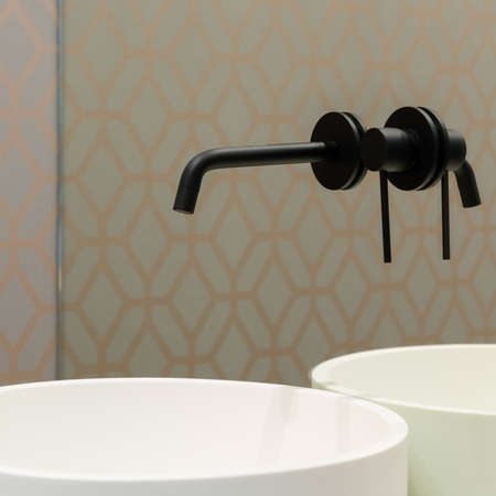 Close-up on elegant black tap in mirror wall over round, white bathroom washbasinの写真素材