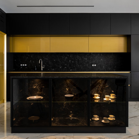 Elegant kitchen island with decorative shelves in exclusive kitchen with gold and black furnitureの写真素材