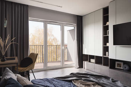 Bright bedroom with window wall, cozy bed and functional deskの写真素材