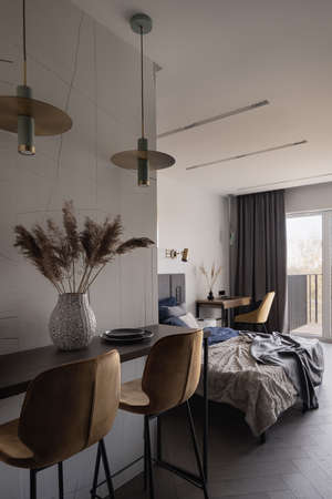 Stylish table with two yellow chairs under two decorative lamps next to bedroomの写真素材