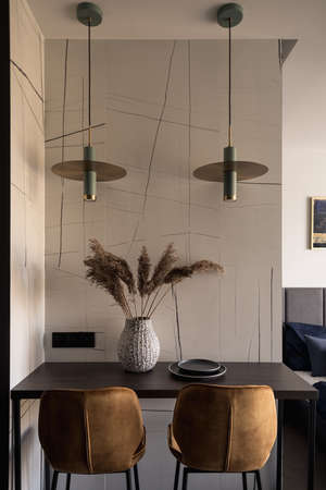 Stylish table with decorations under two modern lamps and with two golden chairsの写真素材
