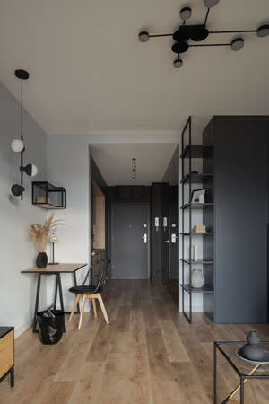 Stylish studio apartment interior with decorative lighting, wooden floor and desk and modern furnitureの写真素材