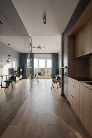 Small and functional kitchen with wooden furniture in apartment corridor with modern mirror wallの写真素材