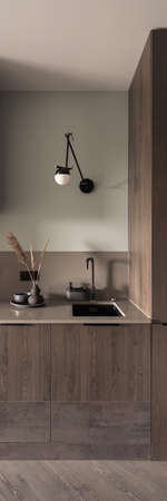Vertical panorama of simple and stylish kitchen with wooden furniture and floor and black detailsの写真素材