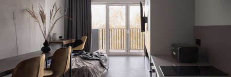 Panorama of small and stylish kitchen with table for two in open studio apartment with window wallの写真素材