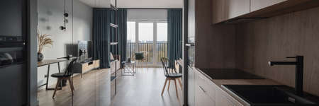 Small and modern kitchen area with wooden furniture and mirror wall stylish open plan apartmentの写真素材
