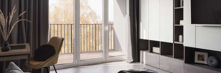 Panorama of bright room with window wall, functional desk with chair and modern furnitureの写真素材