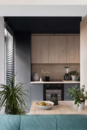 Modern kitchen gray and wooden furniture and small wooden island with decorationsの写真素材