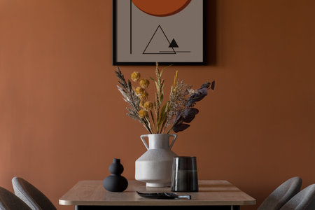 Elegant decorations, vase with flowers and candle on wooden dining table in modern room with art on orange wallの写真素材