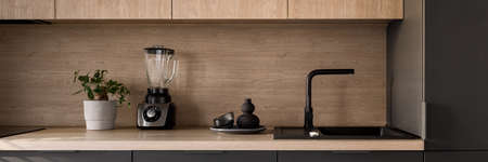 Panorama of wooden kitchen countertop with black sink and tap and decorationsの写真素材