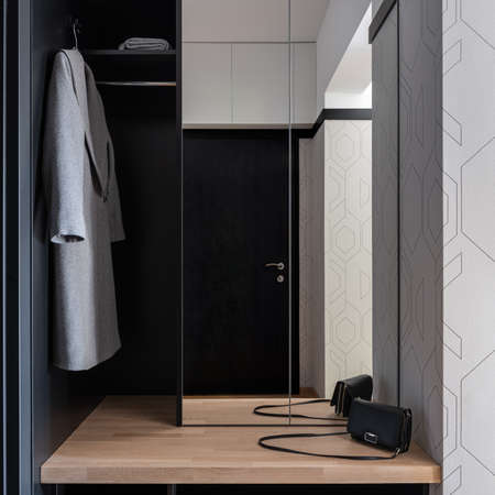 Elegant apartment corridor with black main doors, wardrobe with big mirror and wooden shelfの写真素材