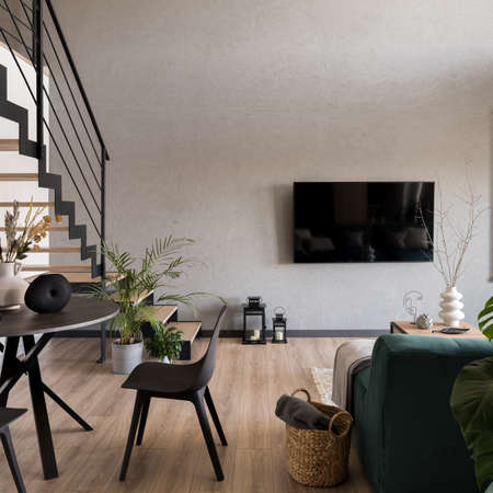 Tv on modern concrete style wall in spacious living room with dining table and stairsの写真素材