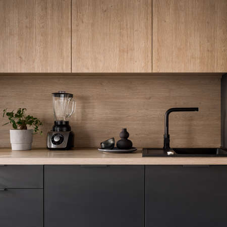 Close-up on wooden kitchen countertop with black sink and tap and decorationsの写真素材