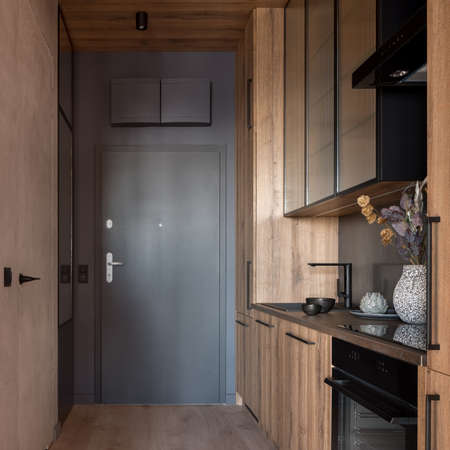 Small and wooden kitchen in corridor with gray main doorsの写真素材