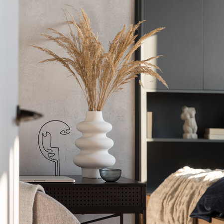 Close-up on white vase with dried grass and decorations on black deskの写真素材