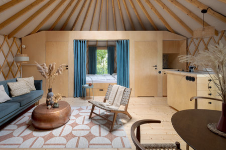 Spacious and stylish yurt interior with cozy bed, living room, kitchen and dining area nicely decoratedの写真素材