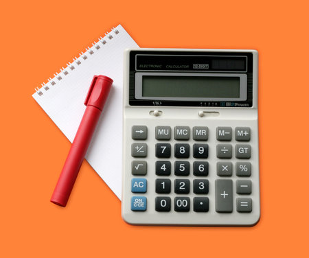 Calculator, marker and note on orange background